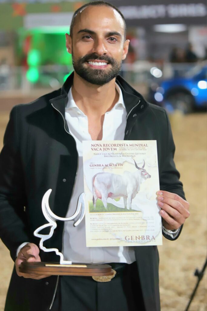 Eros Gazzinelli exibe troféu e cartaz com a imagem de Acácia FIV após anúncio do novo recorde de produção de leite.
